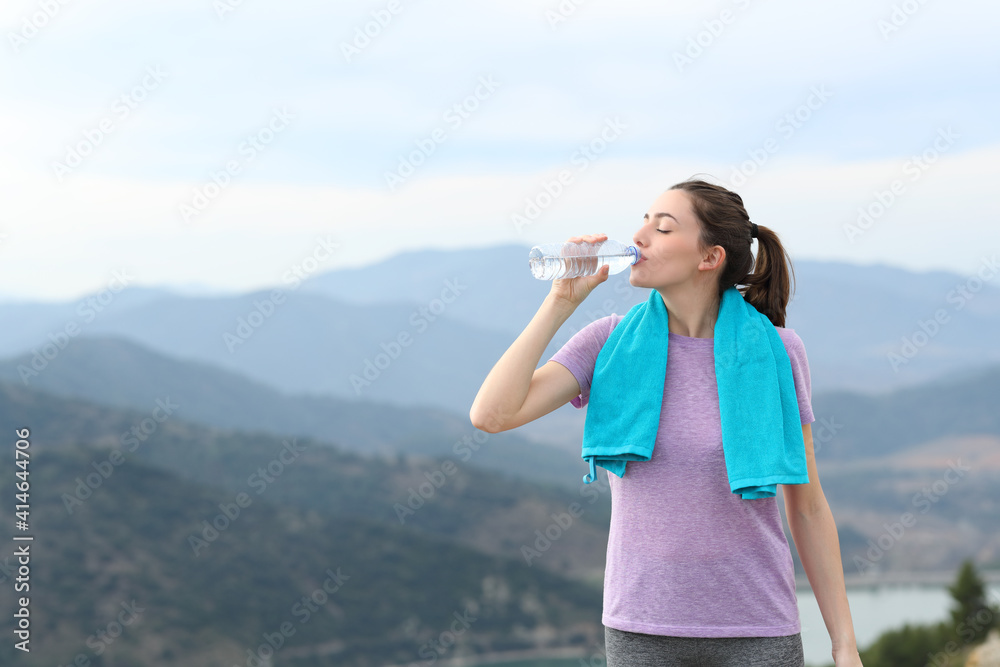 Runner drinking water after sport in the mountain Runner drinking water after sport in the mountain