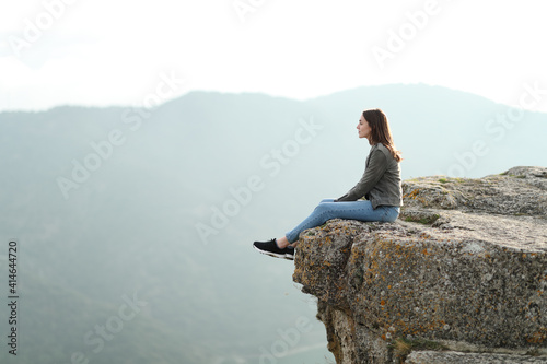 Woman contemplating views on the top of a cliff in the mountain photo