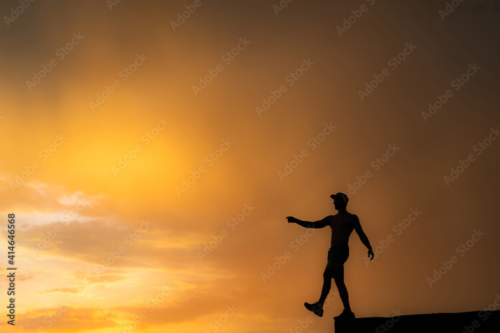 Silhouette of Man stepping from the edge during dramatic sunset. Concept goal, step forward and risk