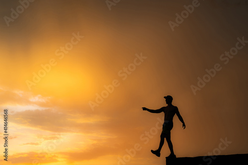 Fototapeta Naklejka Na Ścianę i Meble -  Silhouette of Man stepping from the edge during dramatic sunset. Concept goal, step forward and risk