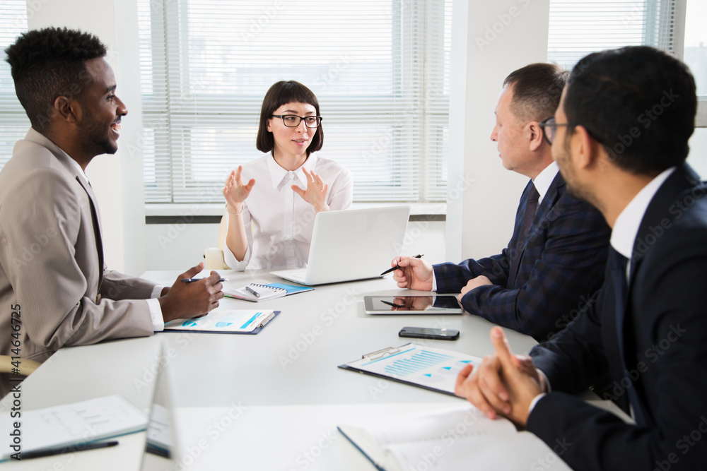 Group of business people sitting around the office desk and discussing the project Group of business people sitting around the office desk and discussing the project