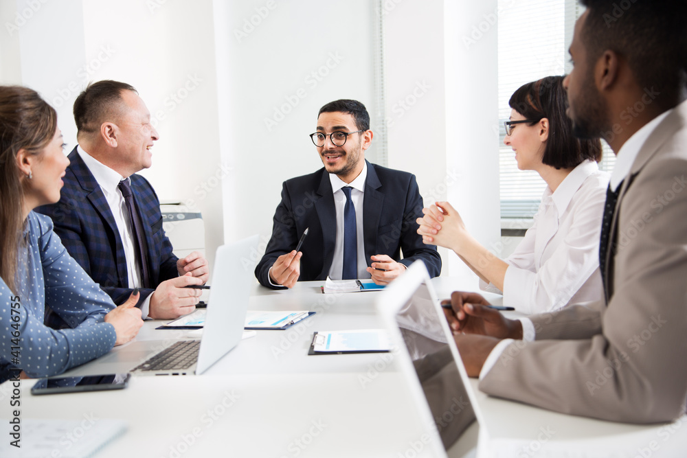 Group of business people sitting around the office desk and discussing the project Group of business people sitting around the office desk and discussing the project