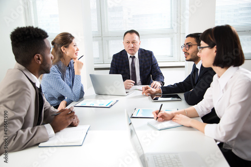 Group of multi-ethnic business people sitting around the office desk and discussing the project