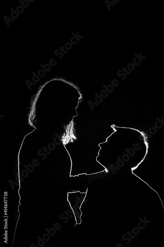 Young couple enjoying outdoors in the forest during night time. Silhouette picture of the couple at the forest with backlight. © Janis Baiks