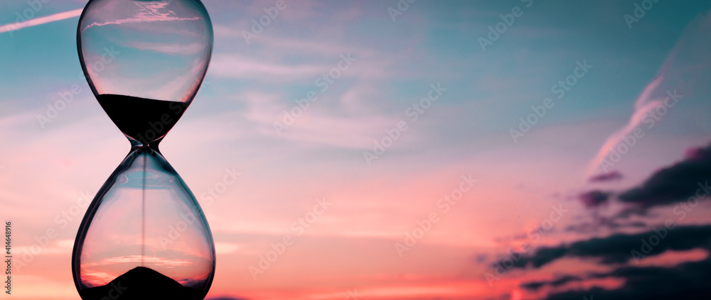 Time passing at sunset with hourglass - obrazy, fototapety, plakaty 