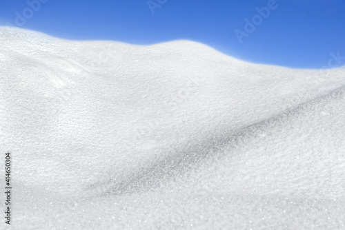 Snow texture or winter white background with wave and blue sky © EKH-Pictures