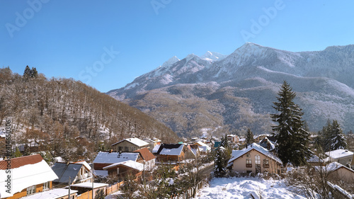 Snow-covered village in the mountains on the background of snow peaks. Ski resort. Sochi, Russia.