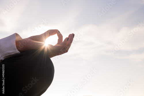 hand with sun beams of a woman meditating