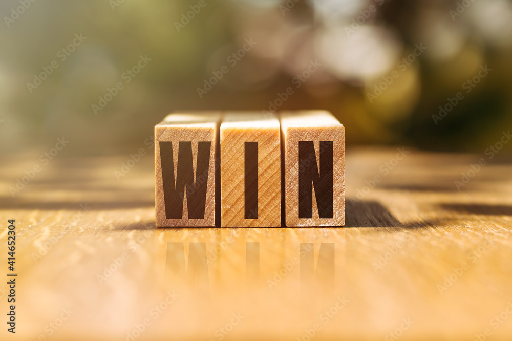 Word WIN made with building wooden blocks on table in sunlight. Word WIN made with building wooden blocks on table in sunlight.