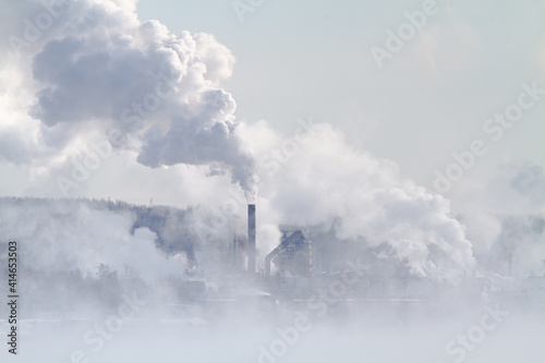 smoke rises from industrial chimneys into the sky