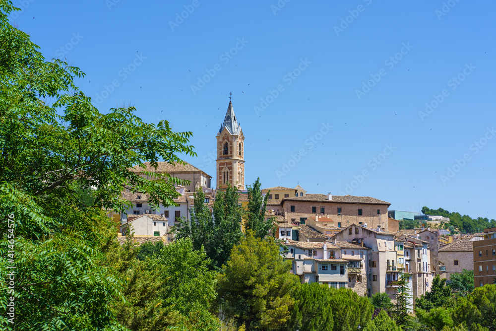 Cityscape with a bell tower surrounded by swallows on a sunny summer day.