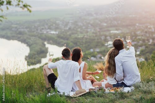 Happy friends enjoying a picnic and beautiful landscape in summer. Togetherness concept with friends. © eduard