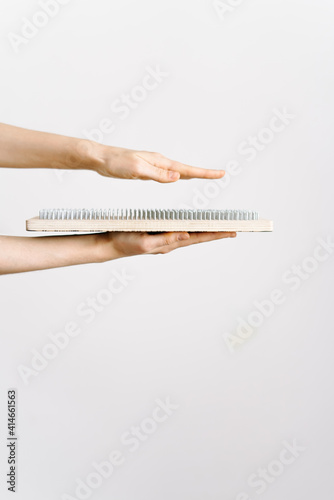 a woman of European appearance holds a wooden board with galvanized nails and puts her hand on top of the nails of the sadhu board. the trend of self-development. the concept of yoga