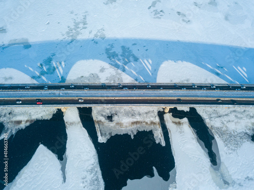 Kyiv metro bridge. A shadow falls on the frozen Dnipro river. Aerial drone view. Winter sunny morning.