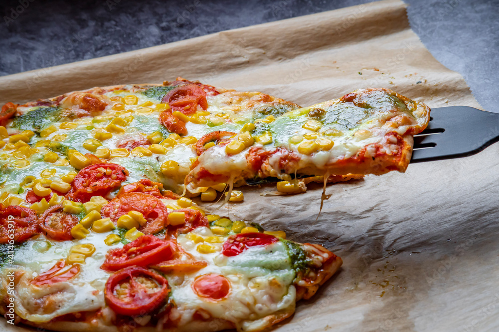 Colorful fresh pizza hot from the oven with mozzarella cheese, corn, pesto and cherry tomatoes