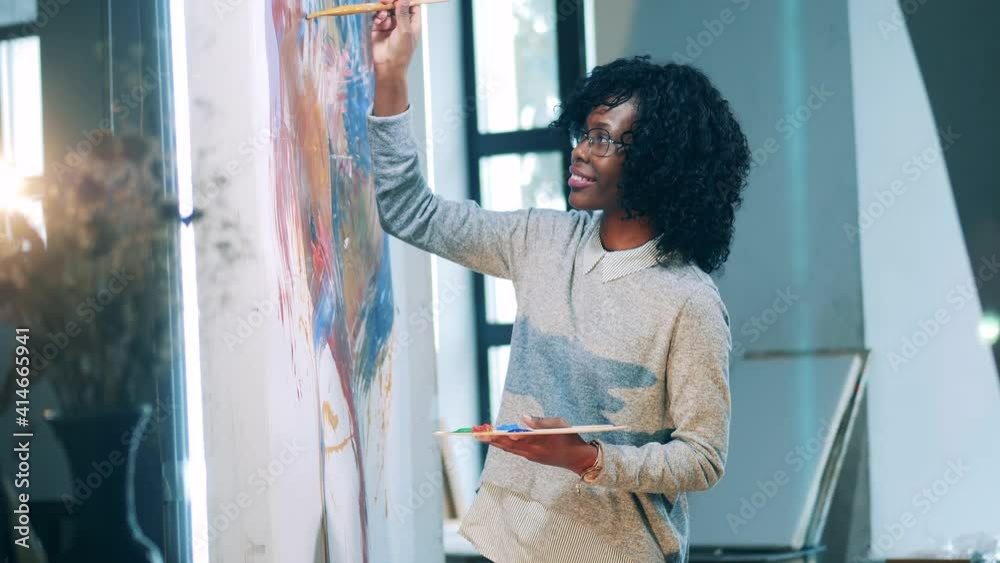 African lady is smiling while painting with a brush