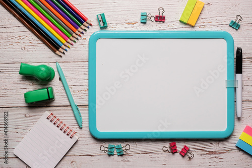 School supplies for homeschool laid out on a white wooden table with a plain white board that can have text and images placed on it