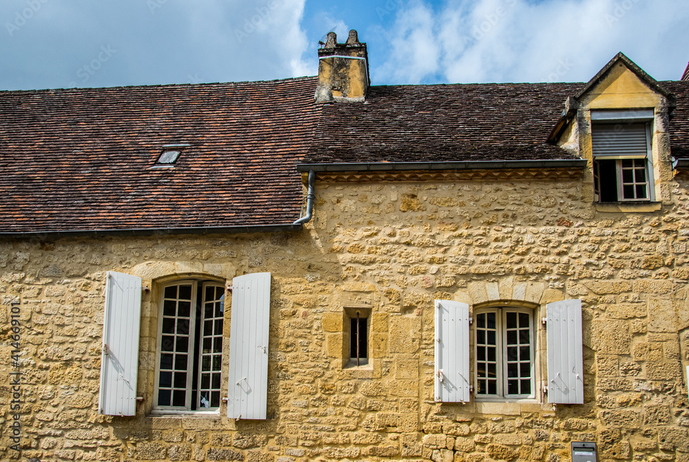 Casas de piedra con ventanas, contraventanas y chimenea en una aldea histórica medieval francesa