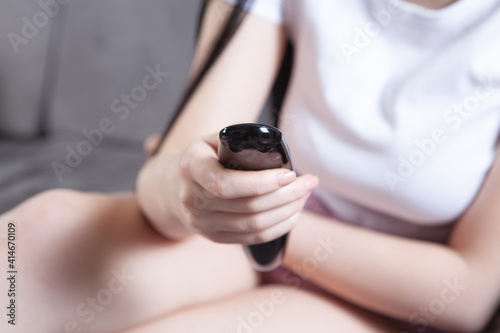 the girl watches TV and holds a remote control in her hands