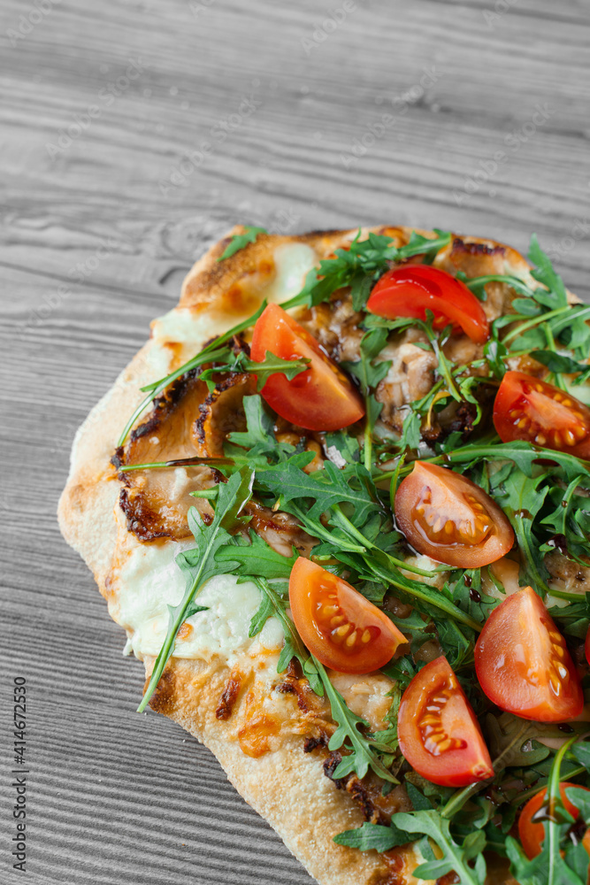 Scrocchiarella gourmet italian cuisine on grey wooden background. Pinsa romana traditional dish. Food delivery from pizzeria. Pinsa with meat, arugula, tomatoes, cheese. Scrocchiarella gourmet italian cuisine on grey wooden background. Pinsa romana traditional dish. Food delivery from pizzeria. Pinsa with meat, arugula, tomatoes, cheese.