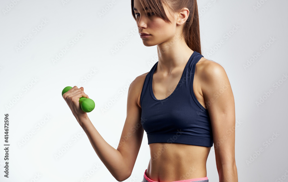 woman with dumbbells in hand on light background cropped view of short t-shirt fitness woman with dumbbells in hand on light background cropped view of short t-shirt fitness