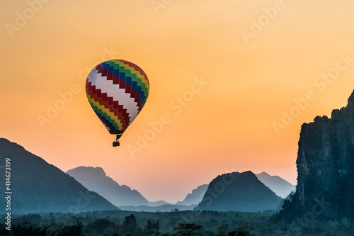 Colorful hot Air ball floats through the misty morning mountain range of Vang Viang in Loas Asia