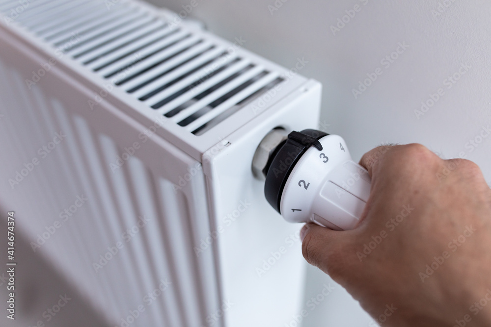 Youmg woman holding temperature knob of heating radiator Youmg woman holding temperature knob of heating radiator