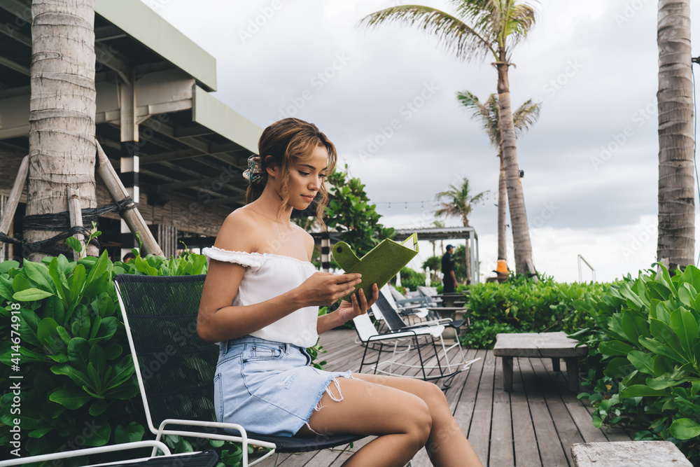Calm ethnic woman reading notebook in outdoor cafe Calm ethnic woman reading notebook in outdoor cafe