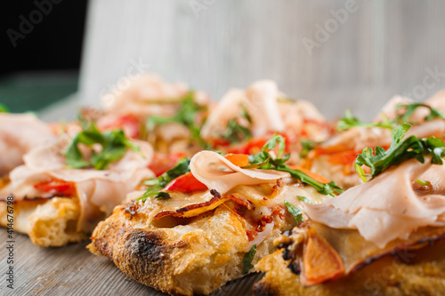 Wallpaper Mural Pinsa romana cut into pieces portions for one person. Food delivery from pizzeria. Pinsa with meat, arugula, cheese. Scrocchiarella gourmet italian cuisine on grey wooden background. Torontodigital.ca
