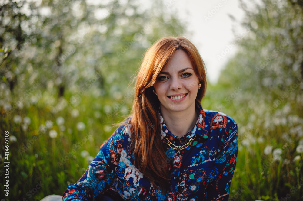 Portrait of a beautiful red-haired girl smiling outdoors. Happy woman on nature background.
