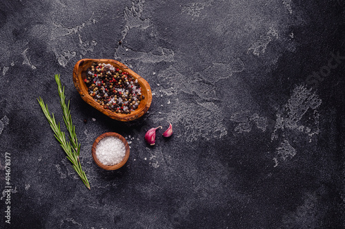 Herbs and condiments on black stone background.