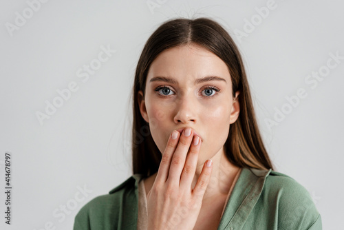 Surprised caucasian girl covering her mouth and looking at camera