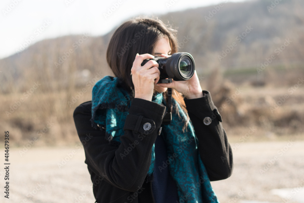 Portrait of a confident young woman black hair close up  standing outside using camera , taking photo  .Woman Taking Picture Outdoors
