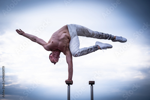 Canvastavla Circus artist keeps balance on one hand on the cloudy sky background