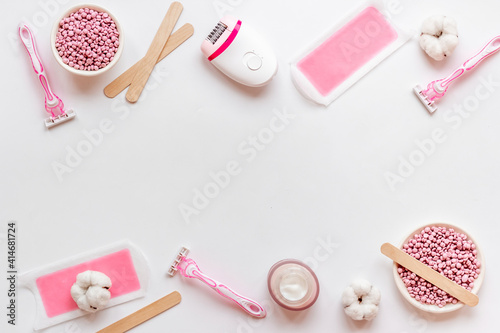 Fototapeta Naklejka Na Ścianę i Meble -  Flat lay of pink epilator with wax strips and razor. Spa cosmetic treatments.