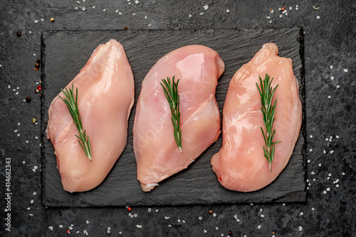 raw chicken breast on a cutting board with spices on a stone background