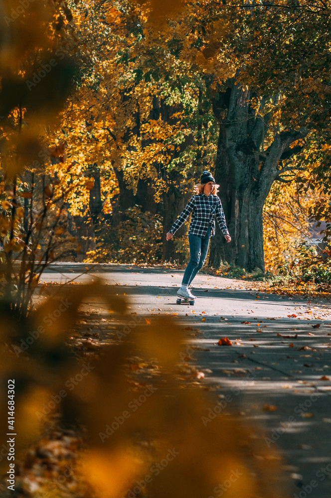 Girl sits on a skateboard.Aerial view of road in autumn with colorful trees. Drone photography. Girl sits on a skateboard.Aerial view of road in autumn with colorful trees. Drone photography.
