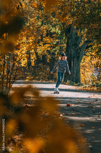 Girl sits on a skateboard.Aerial view of road in autumn with colorful trees. Drone photography.