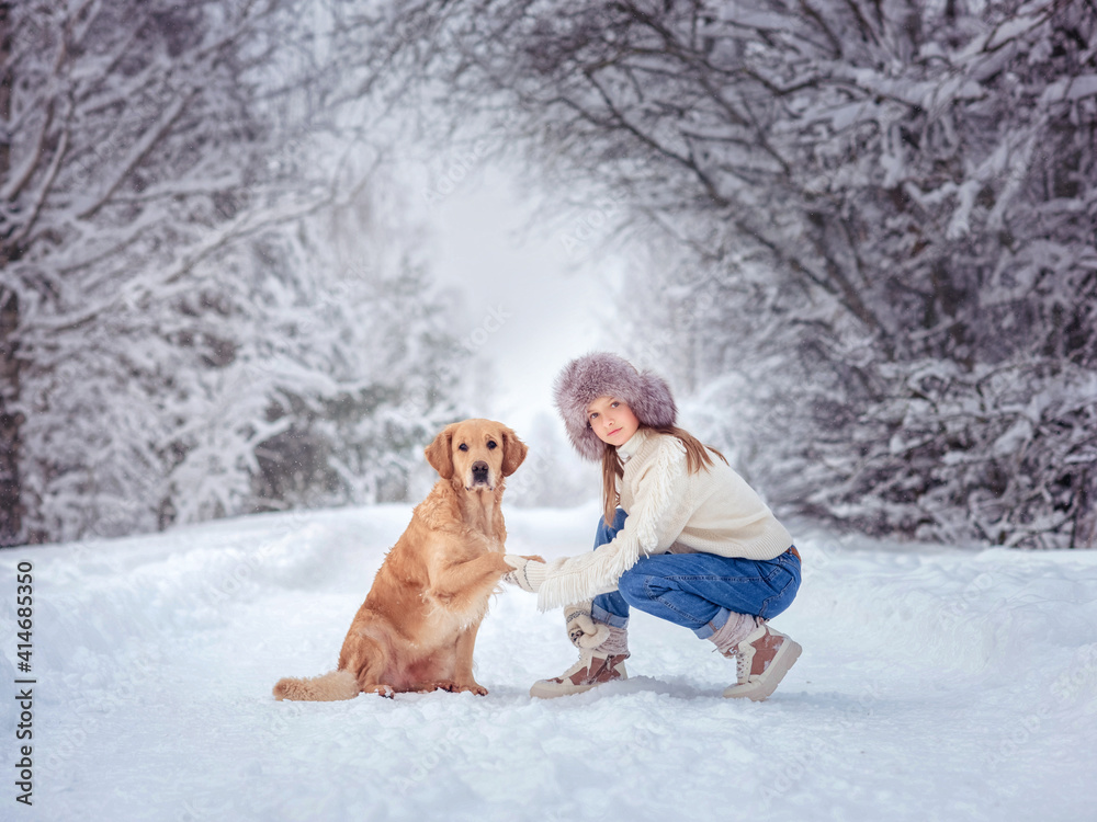 beautiful girl with golden retriever dog in snowing forest