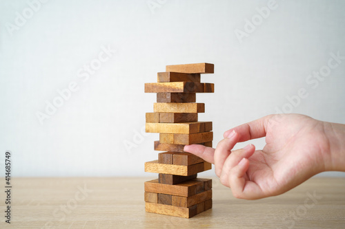 The risk will happen.Hand of engineer playing a blocks wood game on wood table vintage tone. architectural project .as background business concept with copy space.