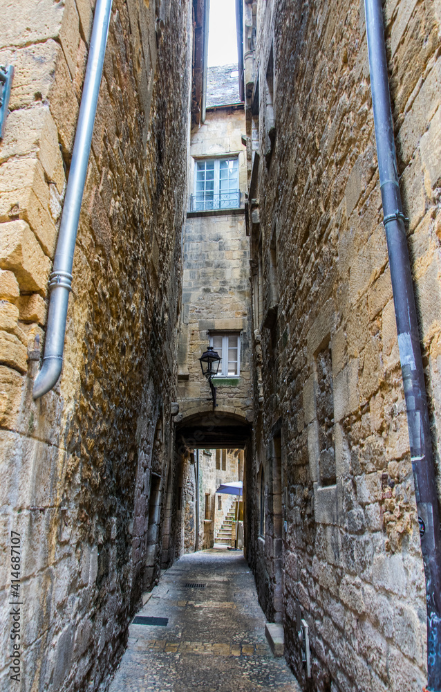 Calle estrecha con canalones, farola, ventanas y arco en una ciudad histórica francesa