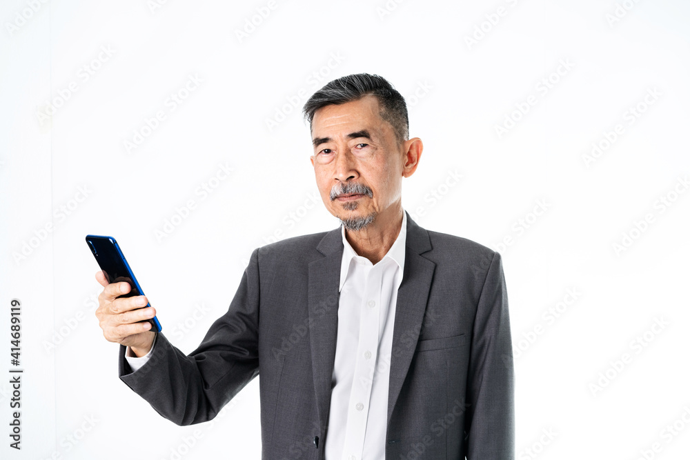 Happy Senior old Asian businessman in grey suit texting and uses the social network on a cell phone. And online Shopping, online technology for the active elder concept. Over white background Happy Senior old Asian businessman in grey suit texting and uses the social network on a cell phone. And online Shopping, online technology for the active elder concept. Over white background