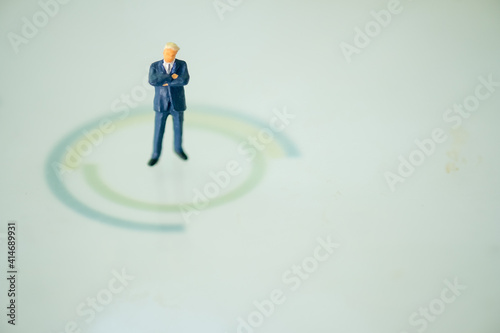 Miniature businessman in suit standing on center of circle. Business strategy conceptual