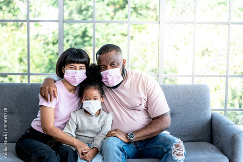 Family, African American father, Asian mother and 5-year-old daughter, they are wearing a surgical mask To prevent the spread of Coronavirus or COVID-19, to family and health care concept.