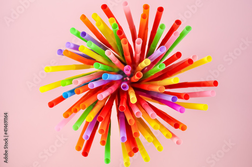 Fotografie Top view of multicolored cocktail plastic straws on a pink background