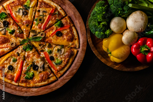 Beautiful photography from top view of yummy pizza with colorful vegetables on black surface. photo