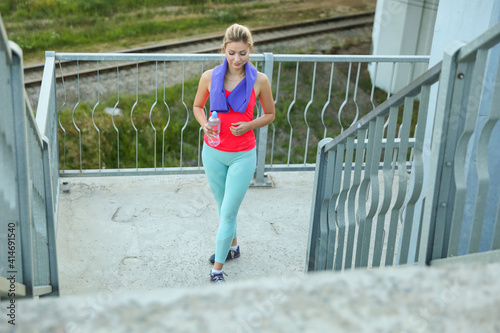 young sporty woman is walking outdoors after fitness exercises