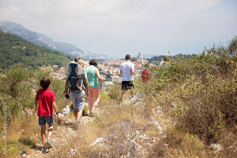 Big family with toddler in a backpack carrier and friends, hiking in the mountains