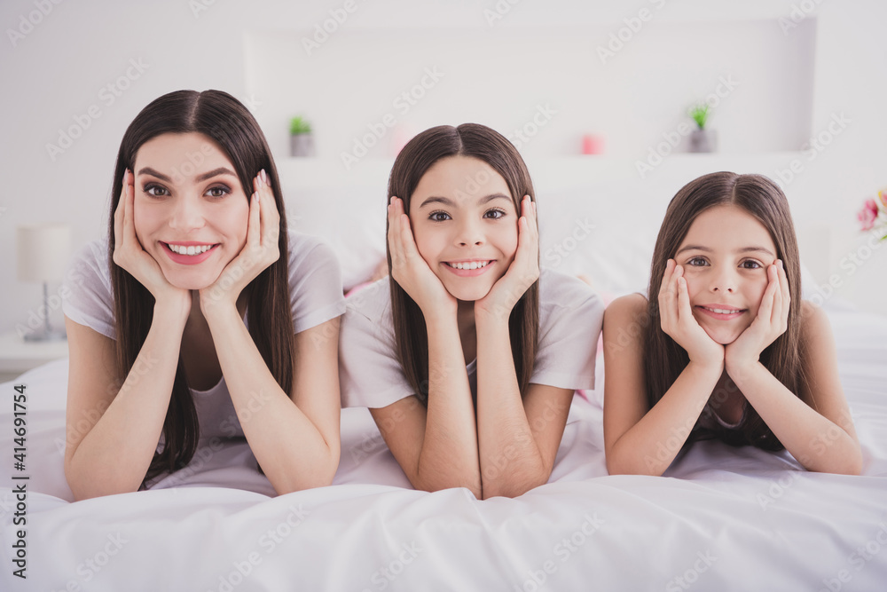 Photo of dreamy pretty three siblings nightwear lying bed arms cheeks smiling indoors inside room home Photo of dreamy pretty three siblings nightwear lying bed arms cheeks smiling indoors inside room home