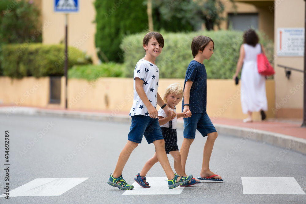Children, boy brothers, siblings holding hands and crossing crosswalk on the street